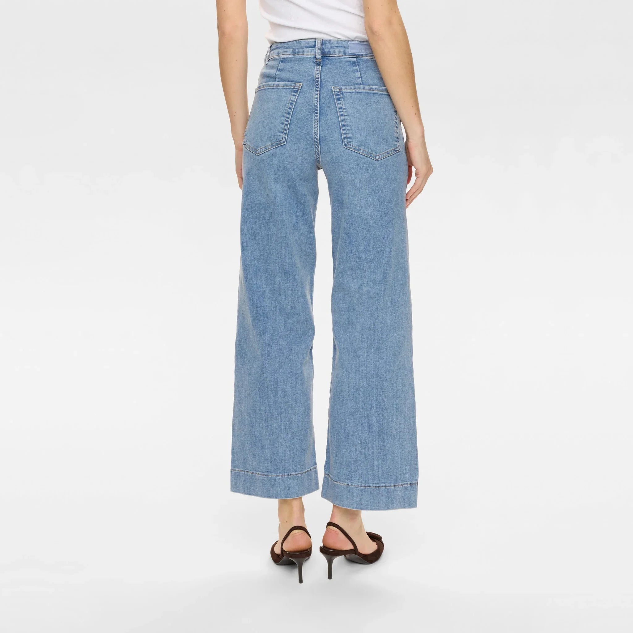 Model i lyseblå Nuparis wide leg jeans set bagfra med baglommer og bred kant forneden