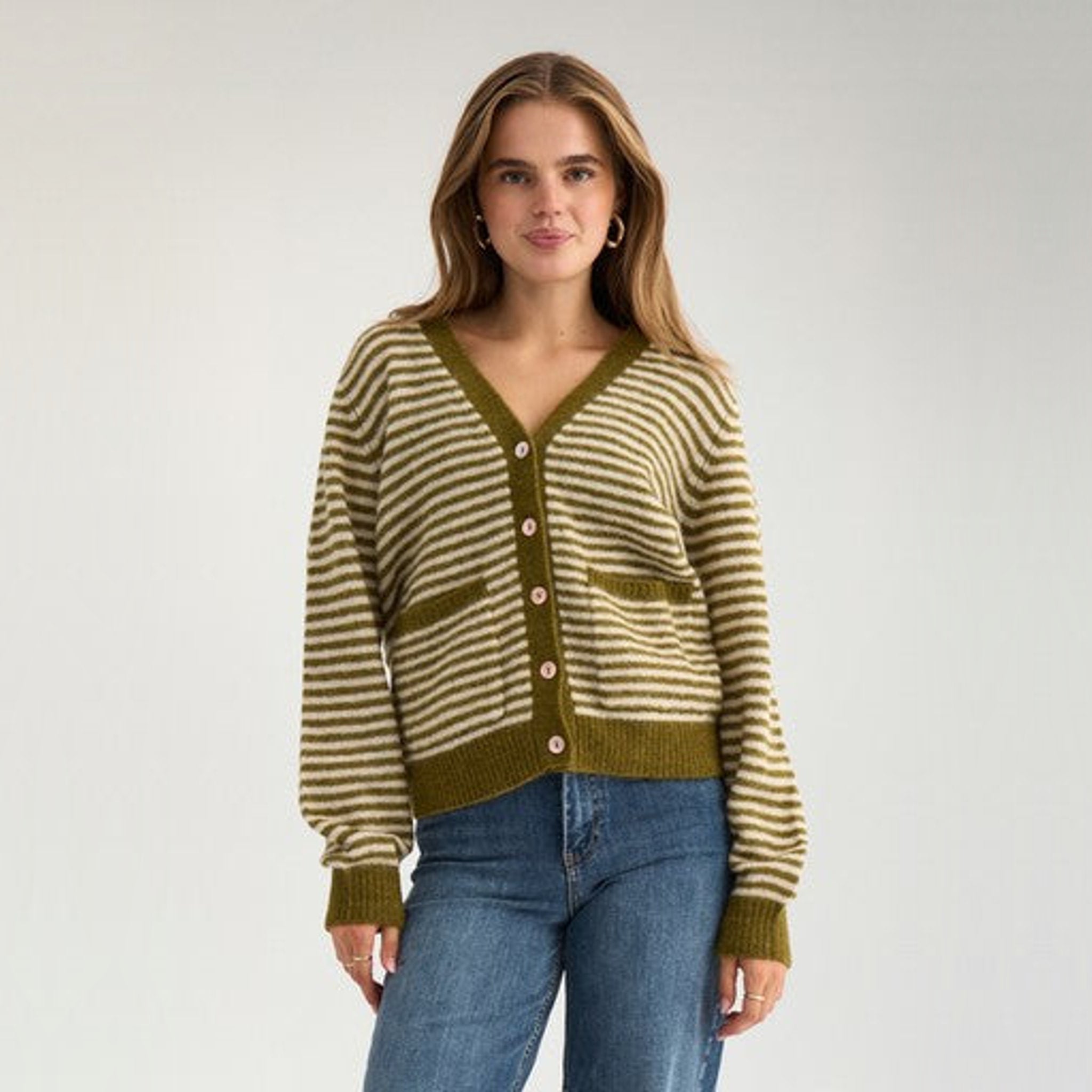 Model i knappet grøn stribet cardigan med V-hals og jeans, set forfra