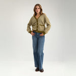 Model i helfigur i grøn stribet cardigan med wide leg jeans og brune loafers