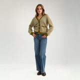 Model i helfigur i grøn stribet cardigan med wide leg jeans og brune loafers