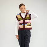 Model i hel figur med den lilla pixelstribede vest, hvid t-shirt og mørke bukser