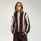 Model i brun pullover med lyserøde striber og brune bukser set forfra