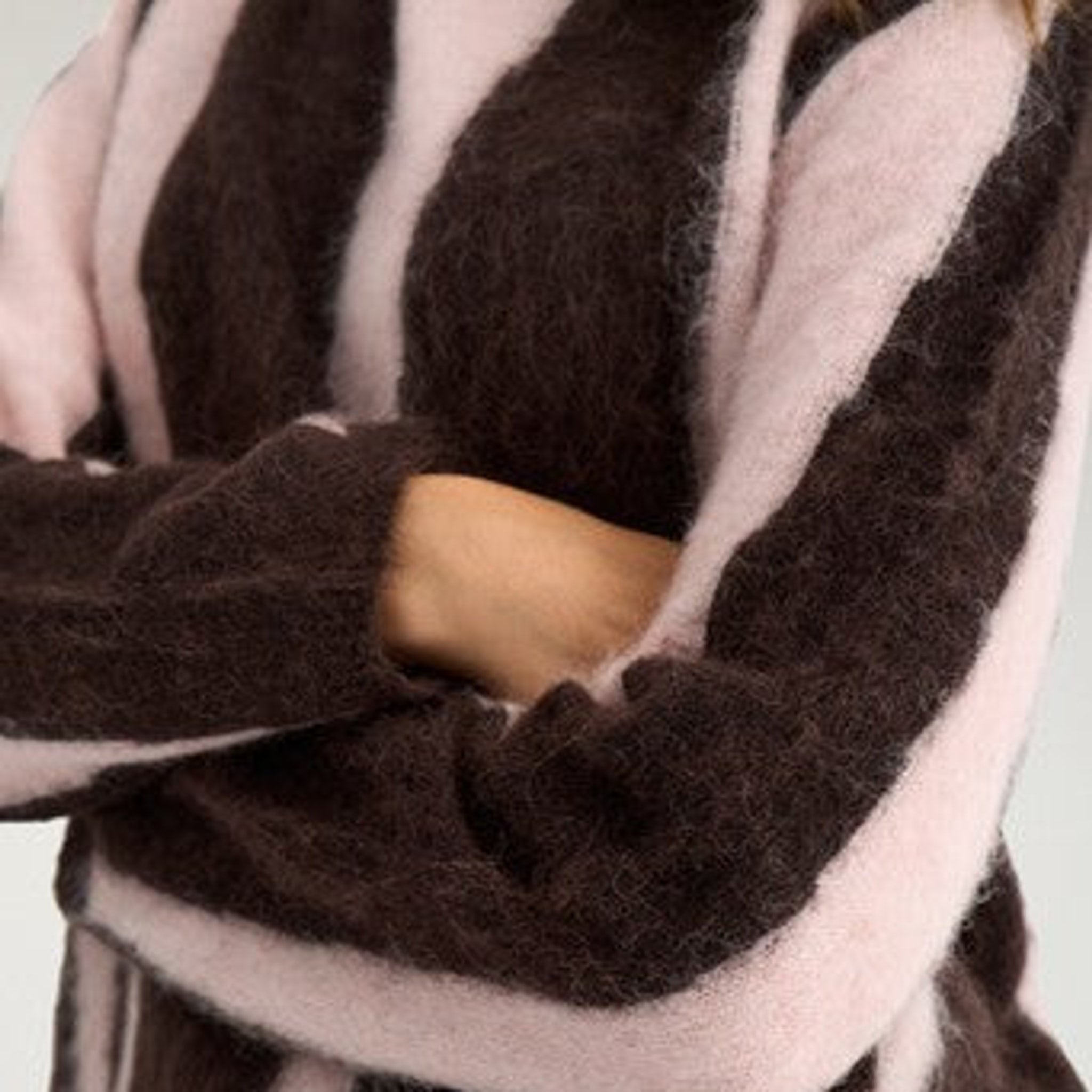 Nærbillede af fluffy strik og lange ærmer på brun pullover med lyserøde striber