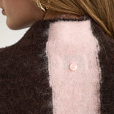 Detalje af lille lyserød knap i nakken på brun stribet pullover