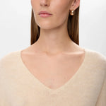 Nærbillede af den dybe V-hals på beige pullover