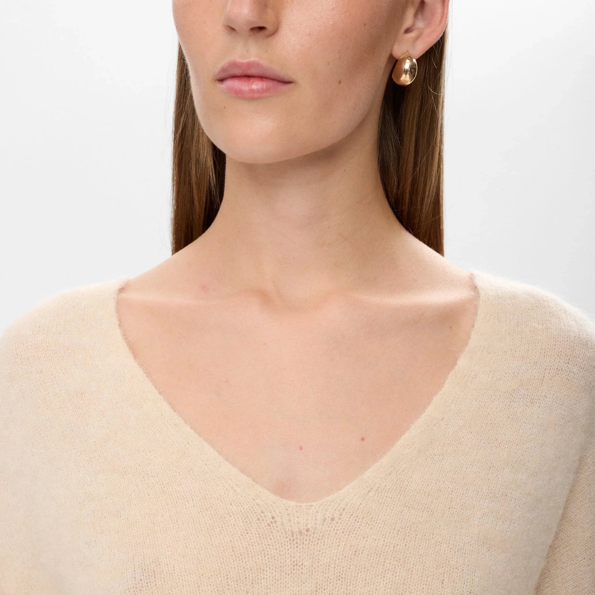 Nærbillede af den dybe V-hals på beige pullover