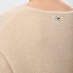 Nærbillede af nakken bagpå beige pullover med lille metalknap