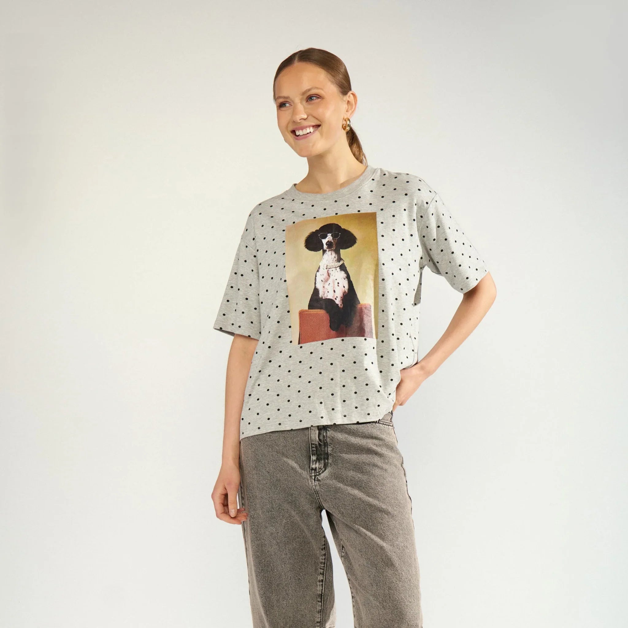Model i hel figur i grå prikket oversize t-shirt med hundeprint, stylet med grå jeans og sorte støvler