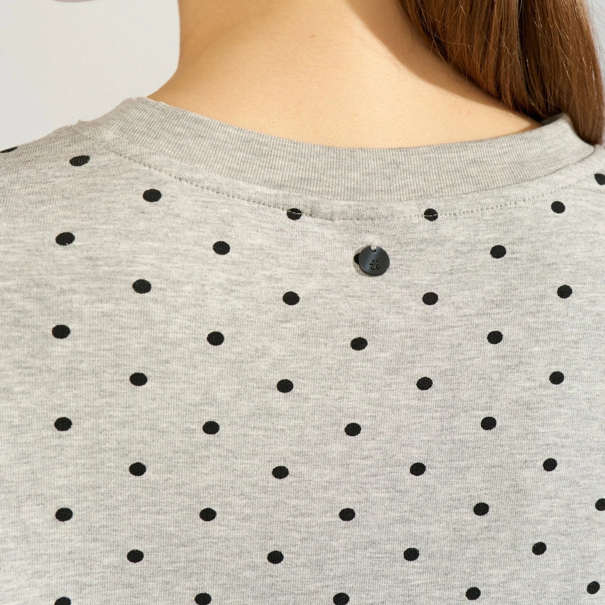 Detalje af rund hals og lille rund detalje bag i nakken på grå prikket t-shirt