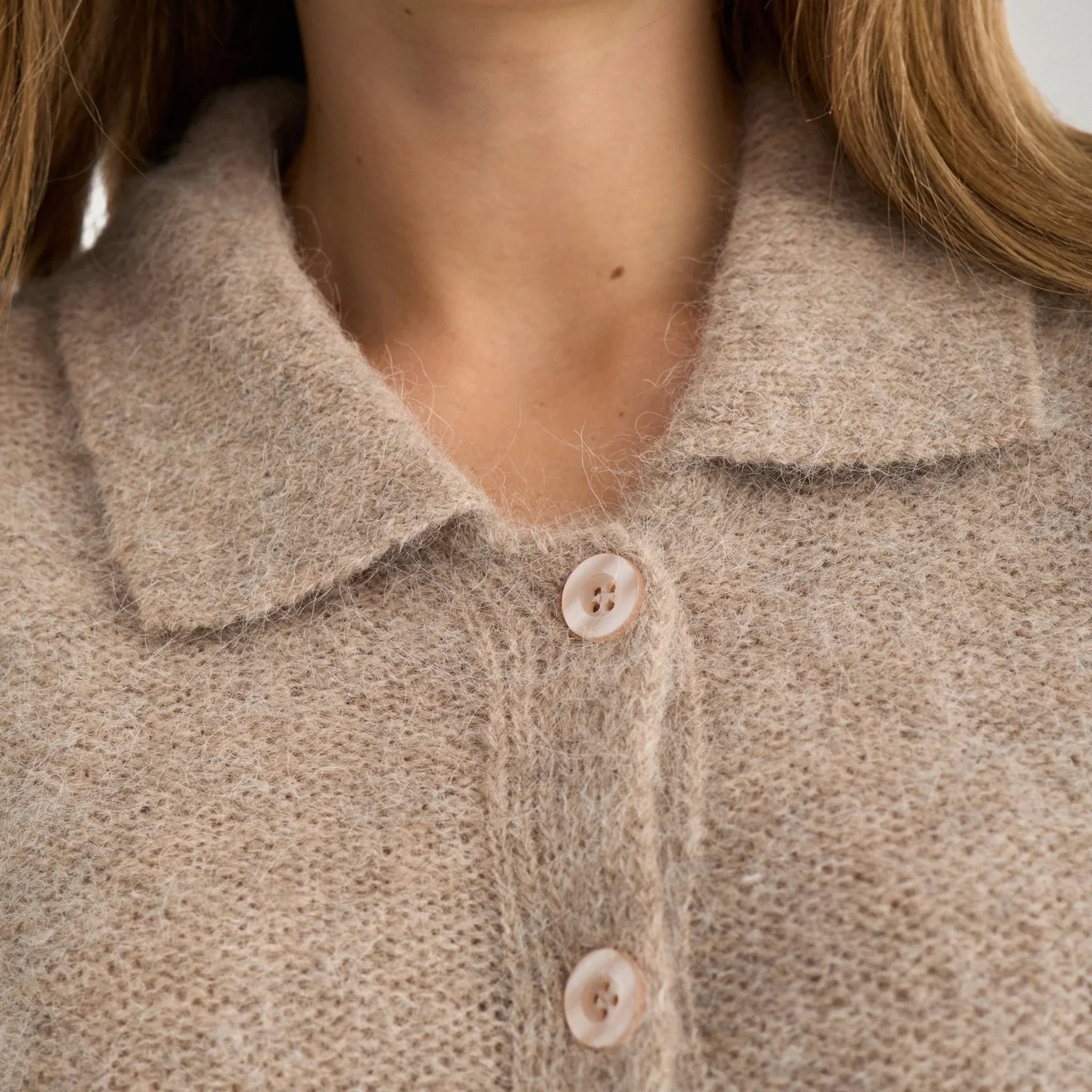 Nærbillede af krave og knapper på beige meleret cardigan