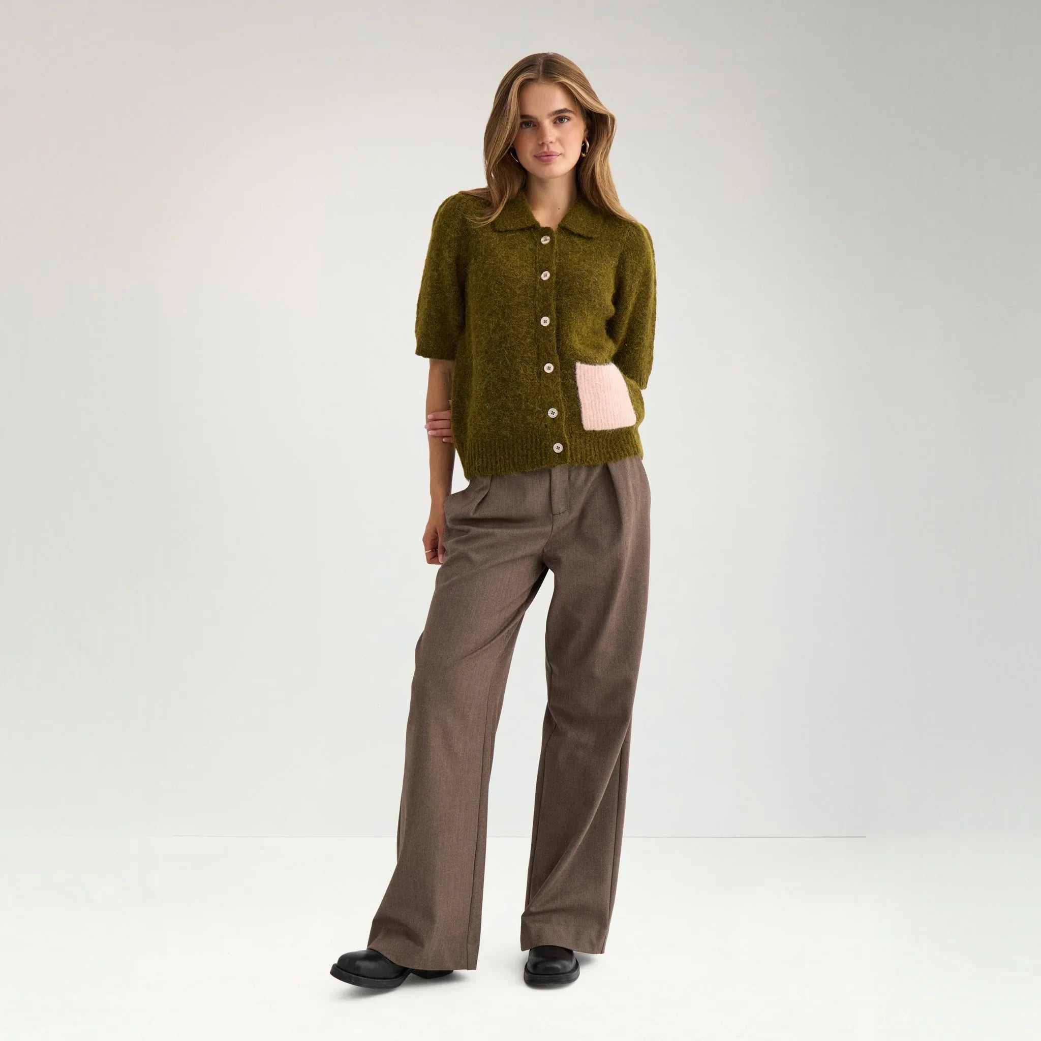 Model i grøn kortærmet cardigan i Fir Green stylet med brune bukser, hel figur