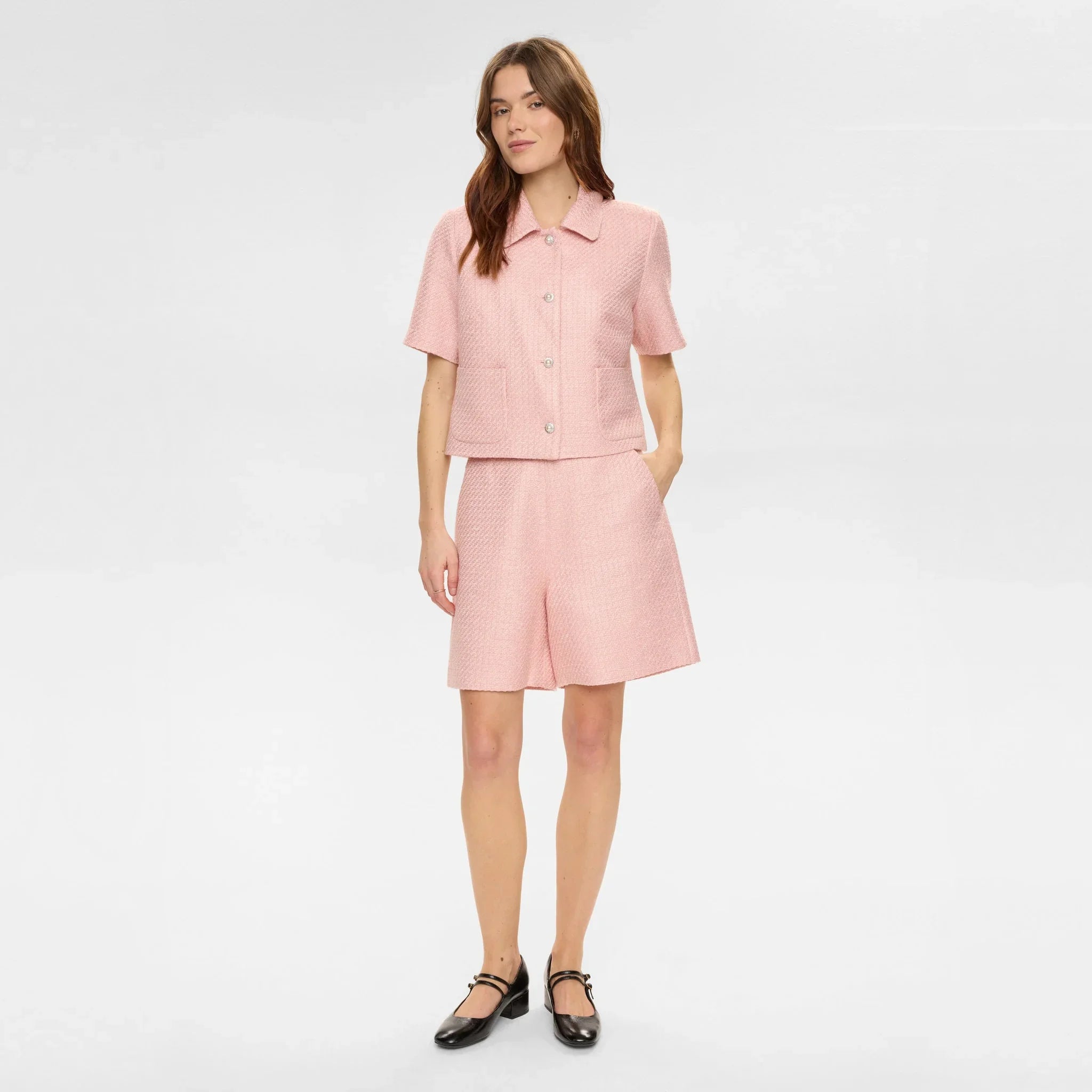 Hel figur af model i pink Nushana jakke med lyserøde shorts og sorte sko