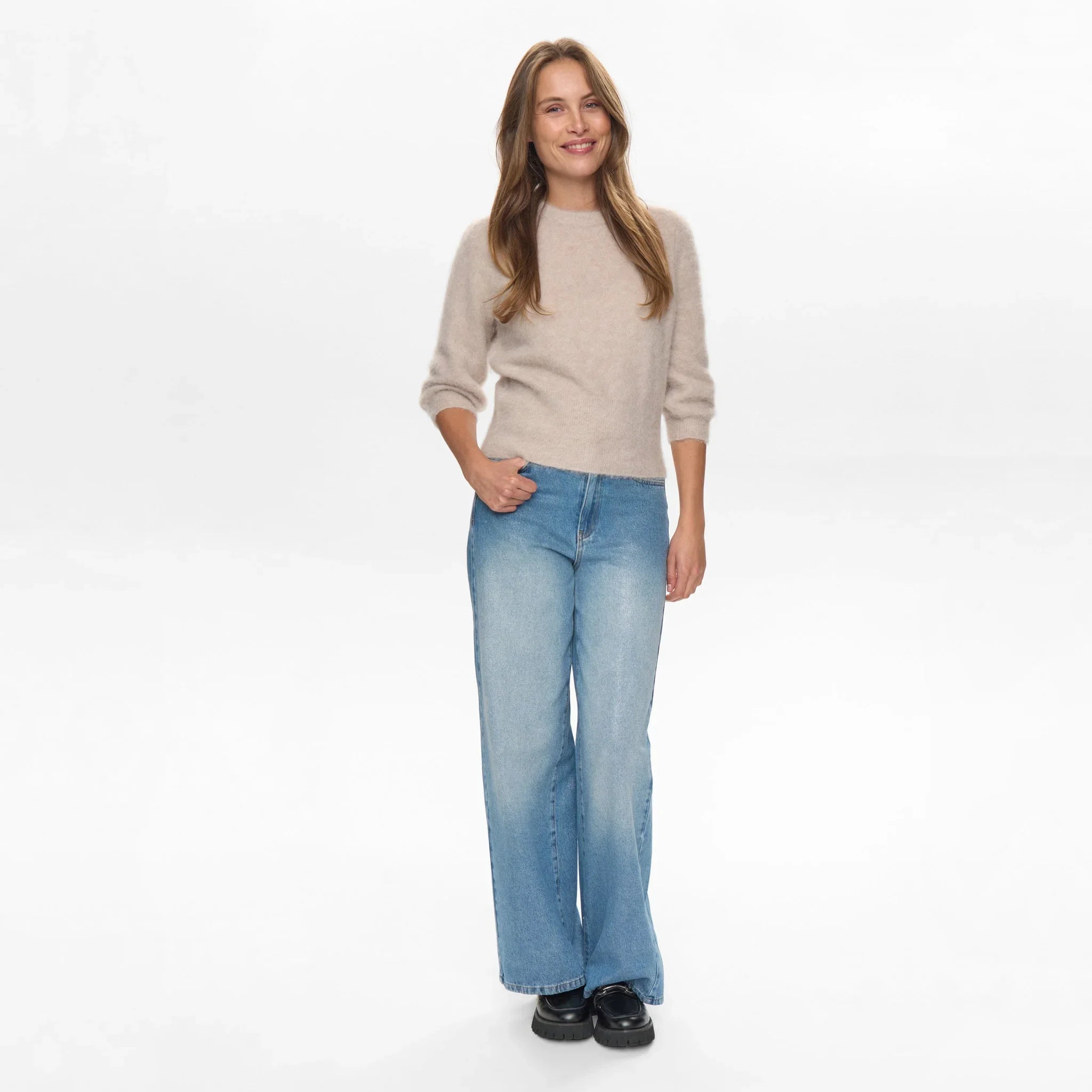 Model i hel figur i grå børstet strik fra Nümph med wide leg jeans og sorte loafers