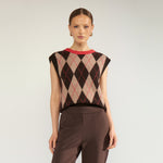 Model i brun og beige argyle vest med rød halskant, stylet med brune bukser, set forfra