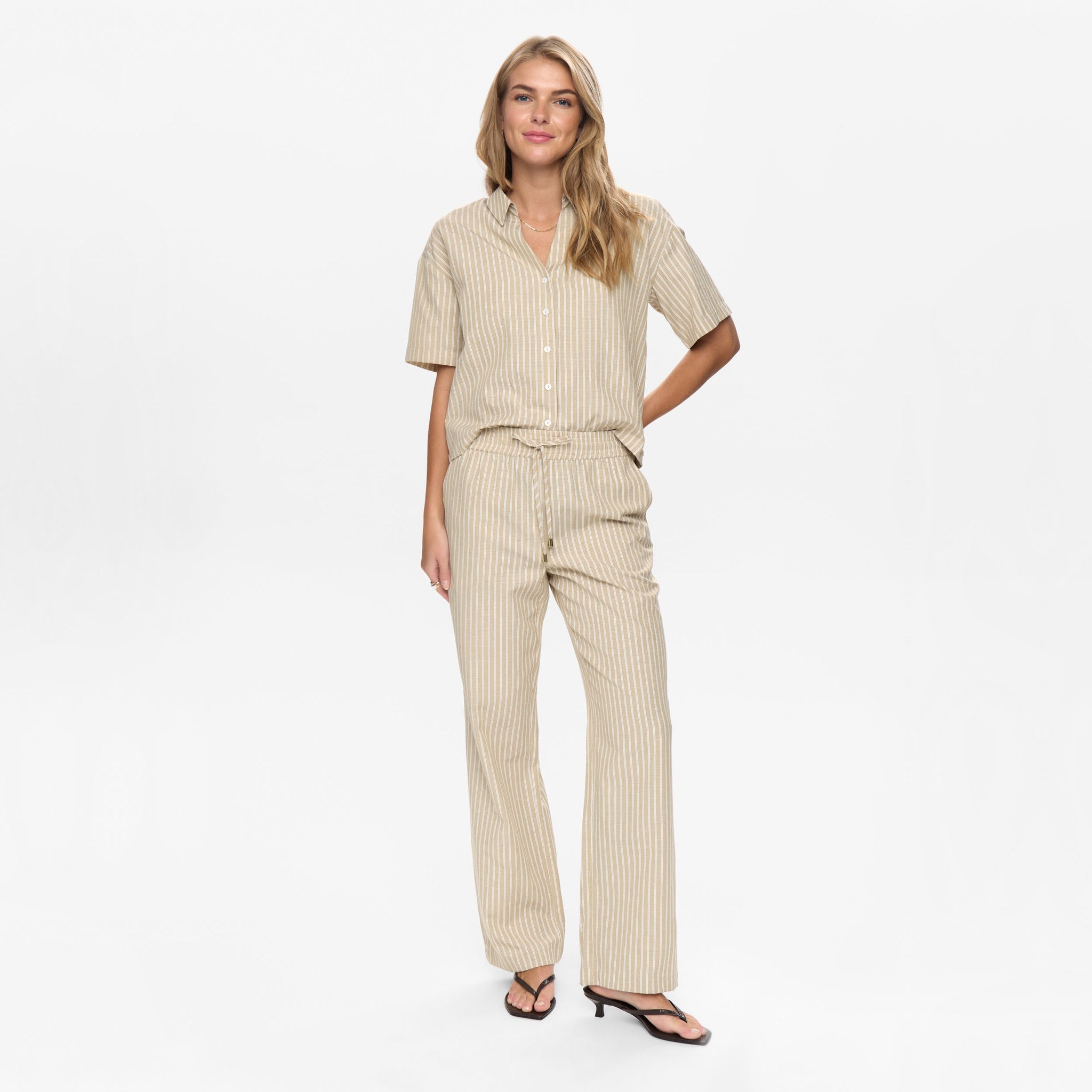 Model i beige stribede wide leg bukser fra Nümph med bindebånd i taljen, hele figuren forfra