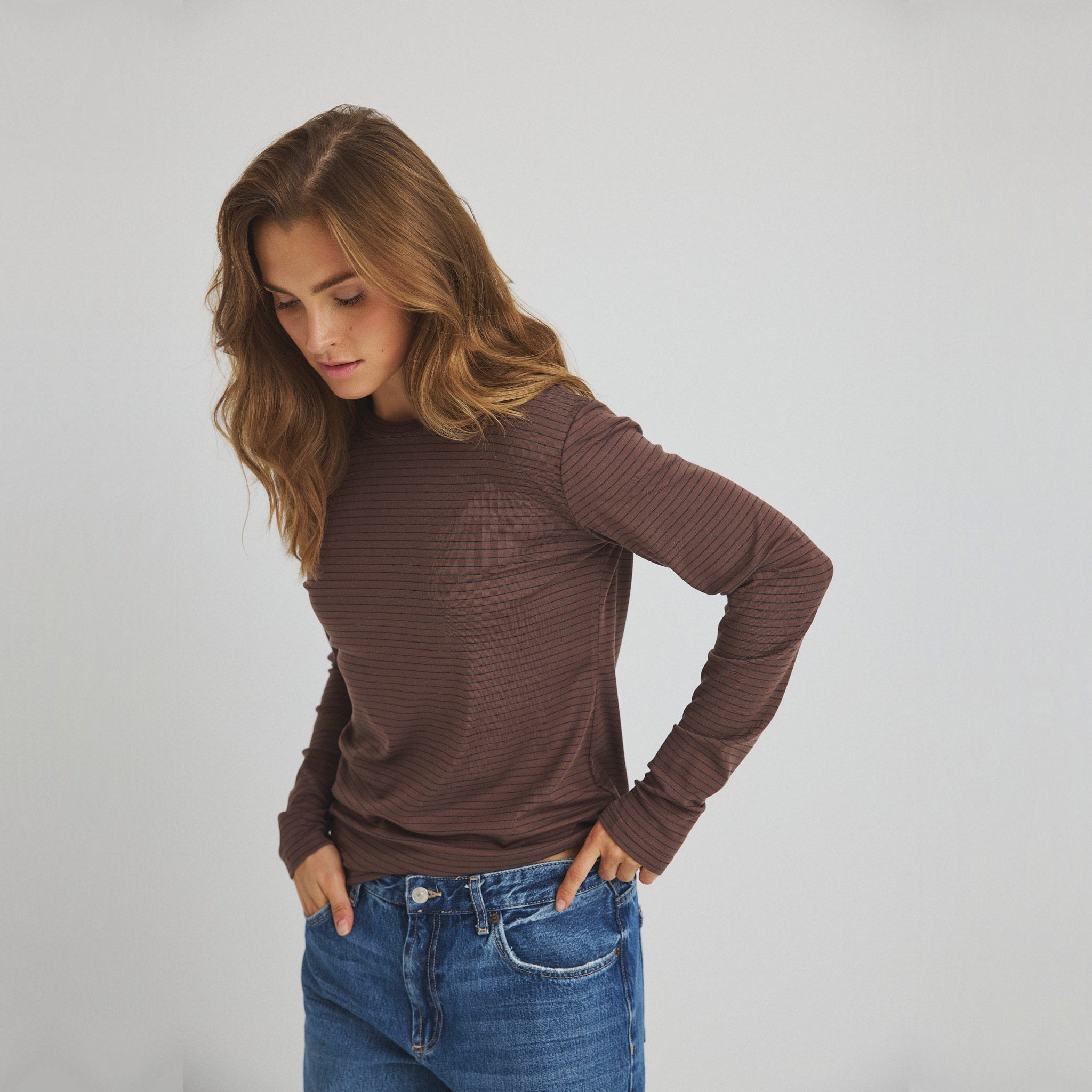 Model i brun stribet langærmet t-shirt stylet med blå jeans