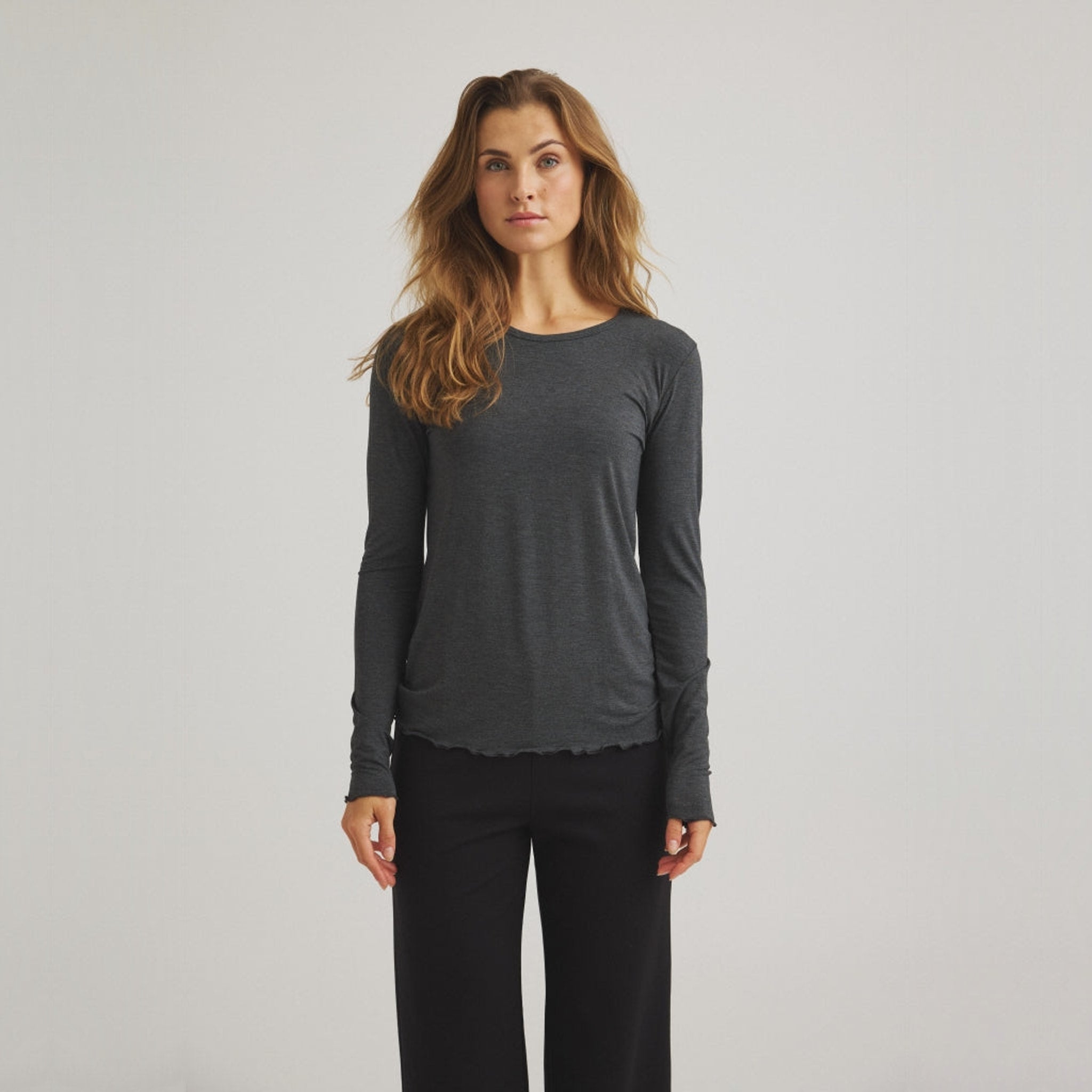 Model i tætsiddende grå langærmet t-shirt fra OneTwo Luxzuz med rund hals, set forfra