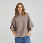 Model i grå strik Zakia i Rain Drum med blå jeans, set forfra