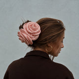 Model set bagfra med pink satinrose-hårklemme i farven Nude i en opsat knold