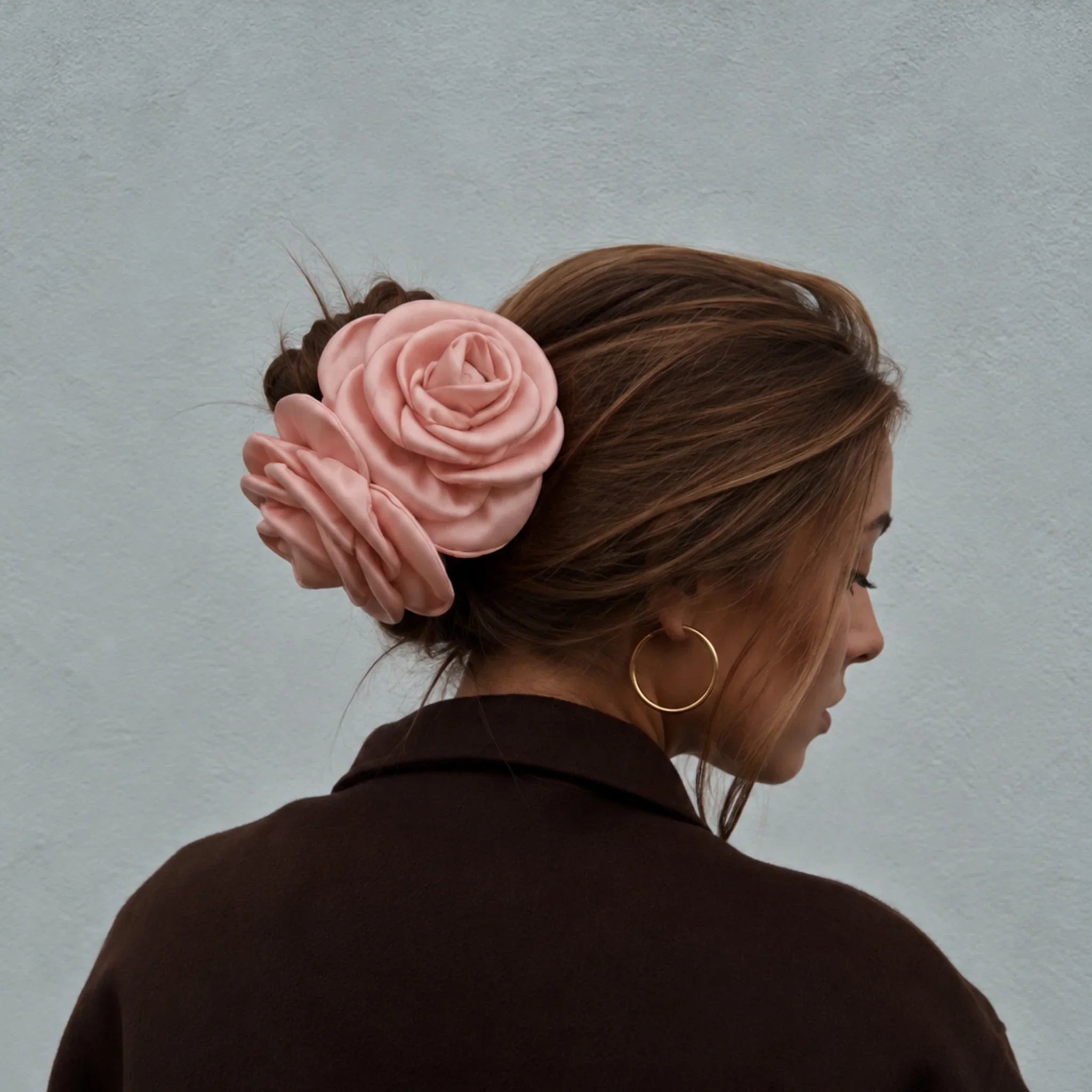 Model set bagfra med pink satinrose-hårklemme i farven Nude i en opsat knold