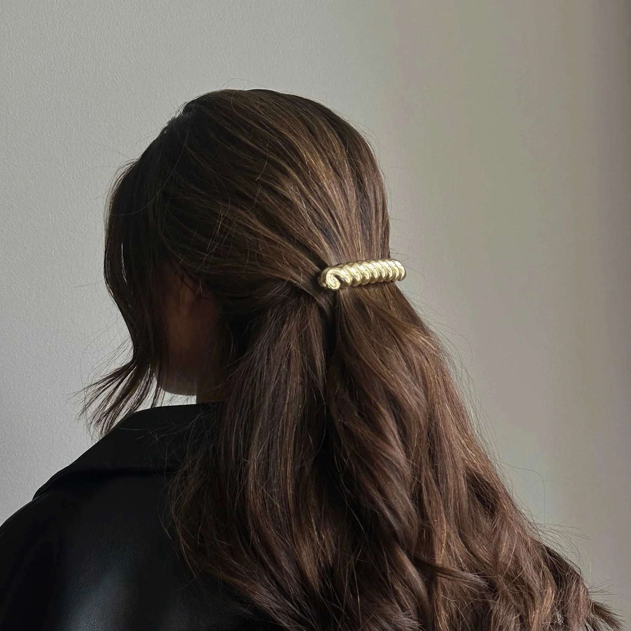 Model bagfra med langt brunt hår i halv opsætning, holdt af Jeanne Barette i guld fra Pico