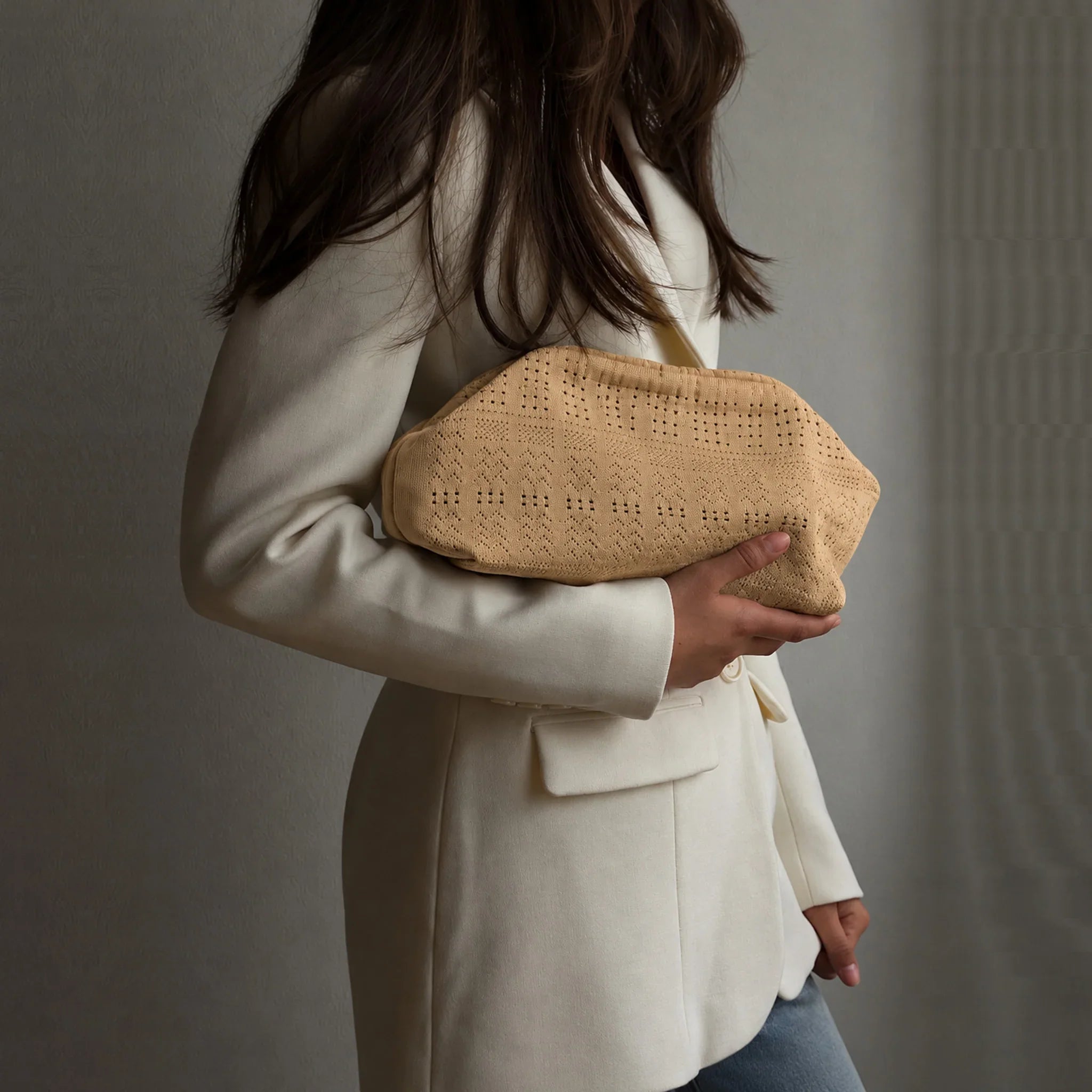 Model holder beige Rosalia Clutch taske med hulmønster under armen