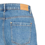 Detalje af baglomme med nitter i guldfarve og Pulz Jeans-mærkat på blå jeans
