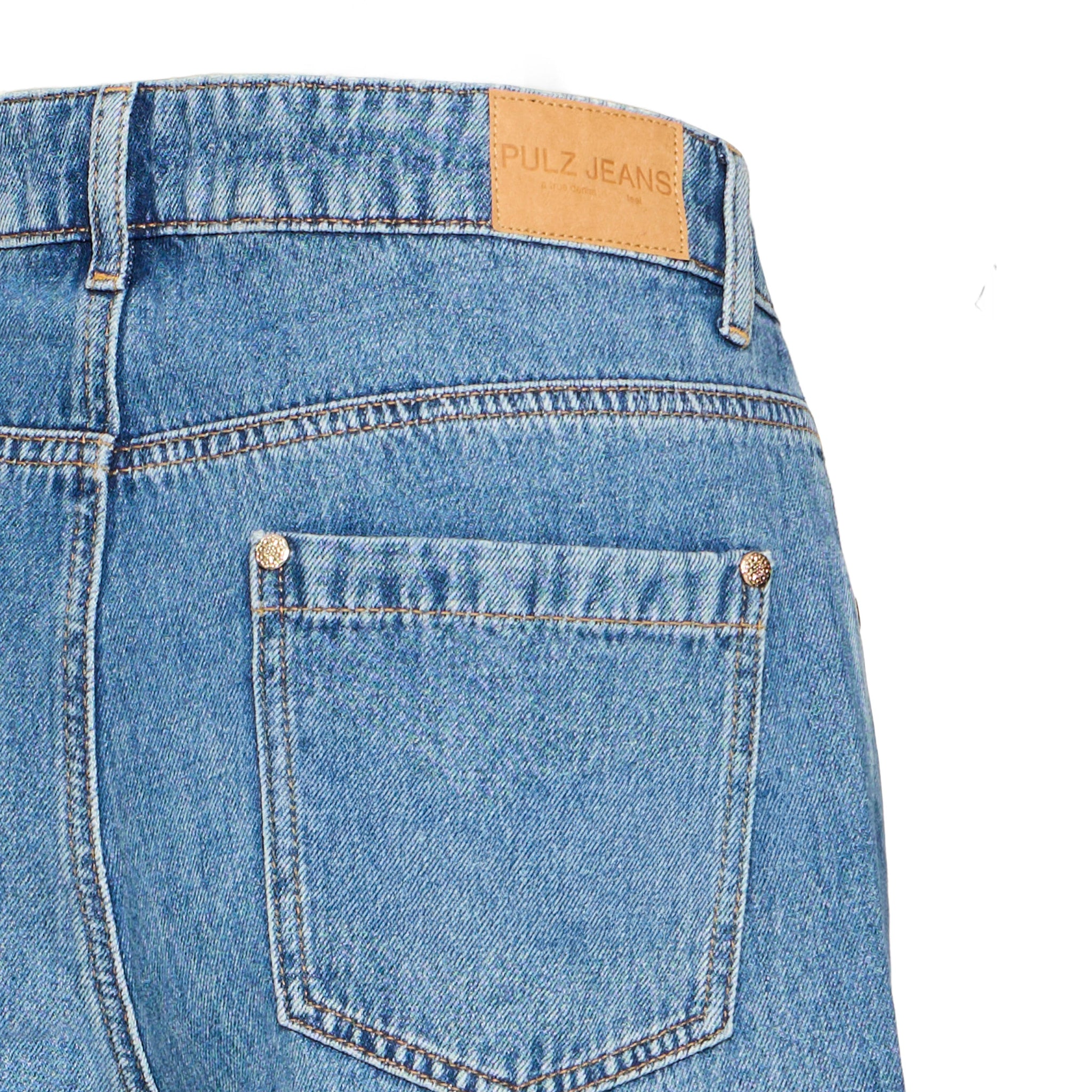 Detalje af baglomme med nitter i guldfarve og Pulz Jeans-mærkat på blå jeans