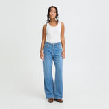 Model i blå April wide leg jeans med høj talje, stylet med hvid tanktop og brune støvler