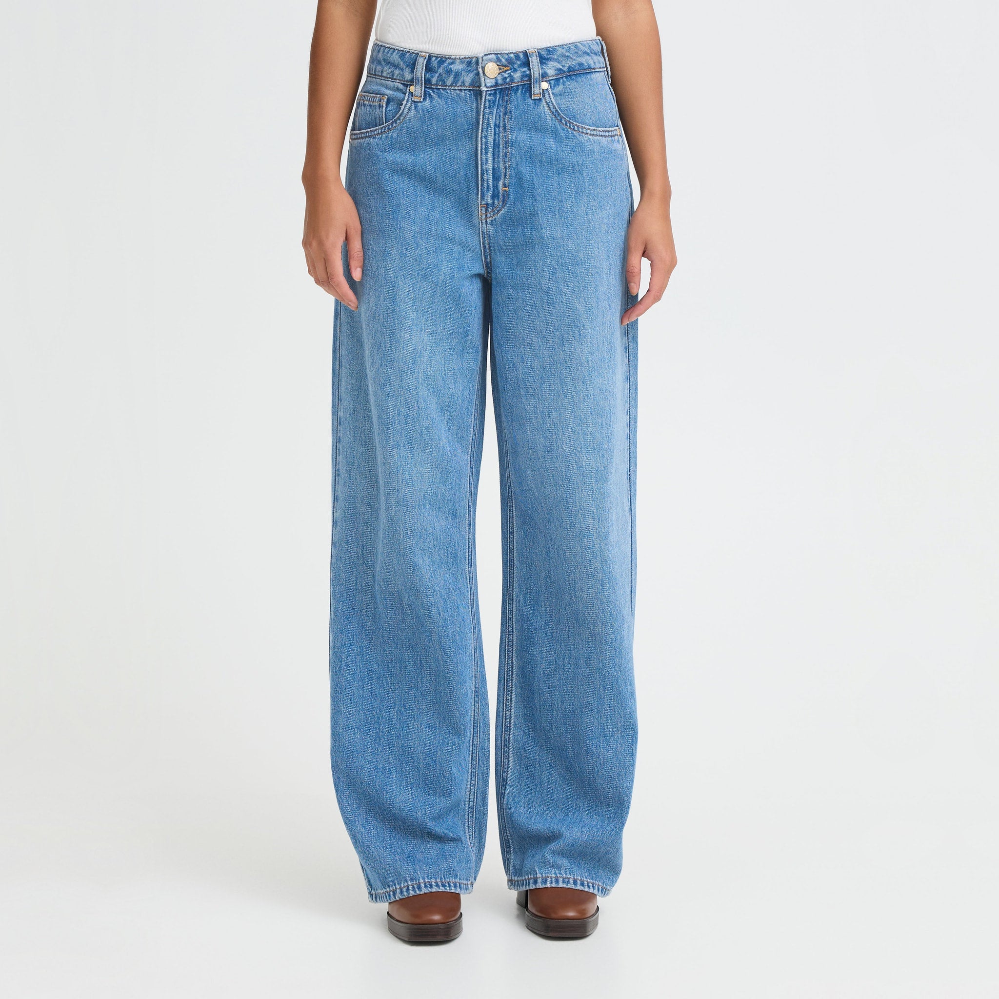Tæt på model i blå wide leg jeans set forfra med brede ben og knaplukning