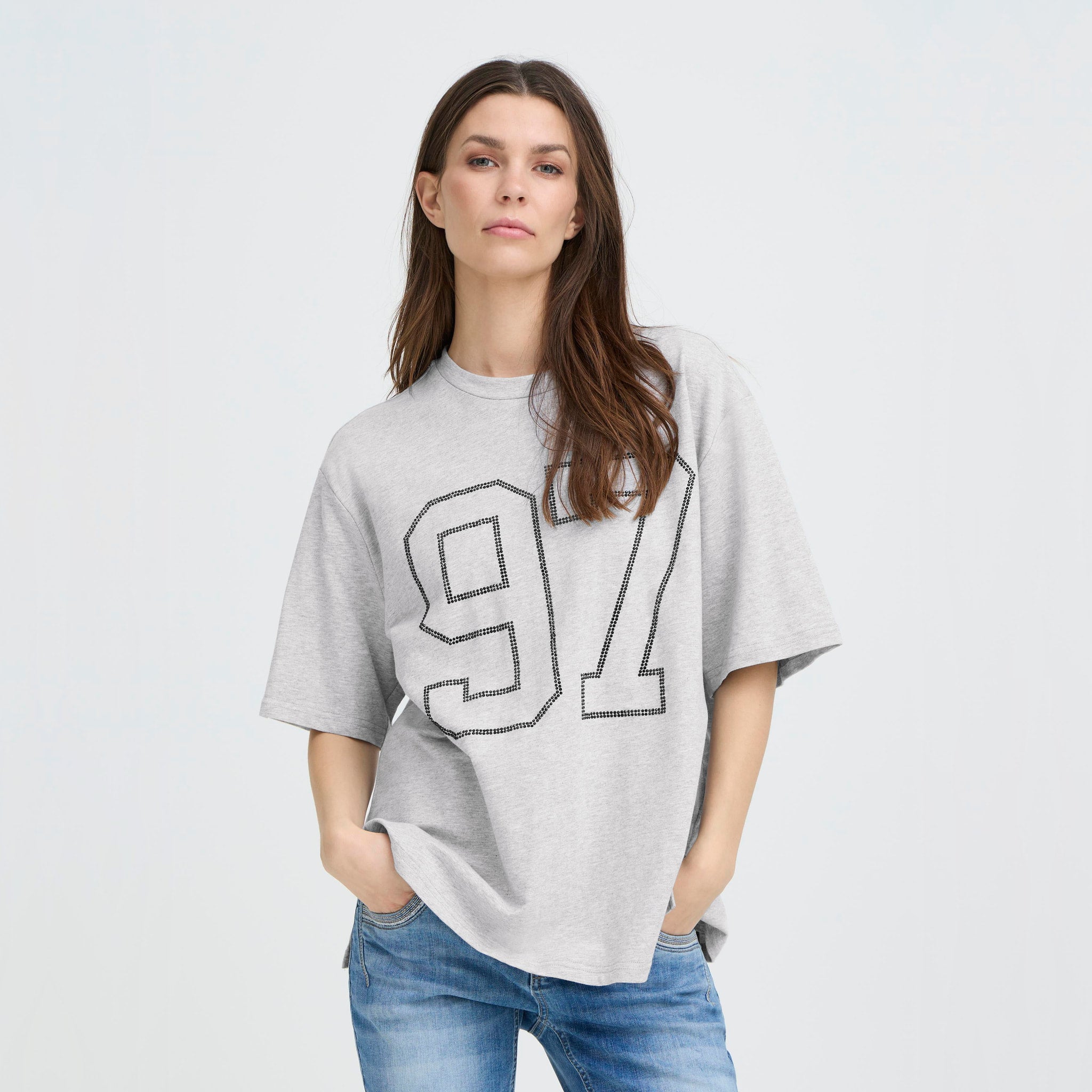 Model med hænderne i lommerne i løs grå t-shirt fra Pulz med 97-motiv