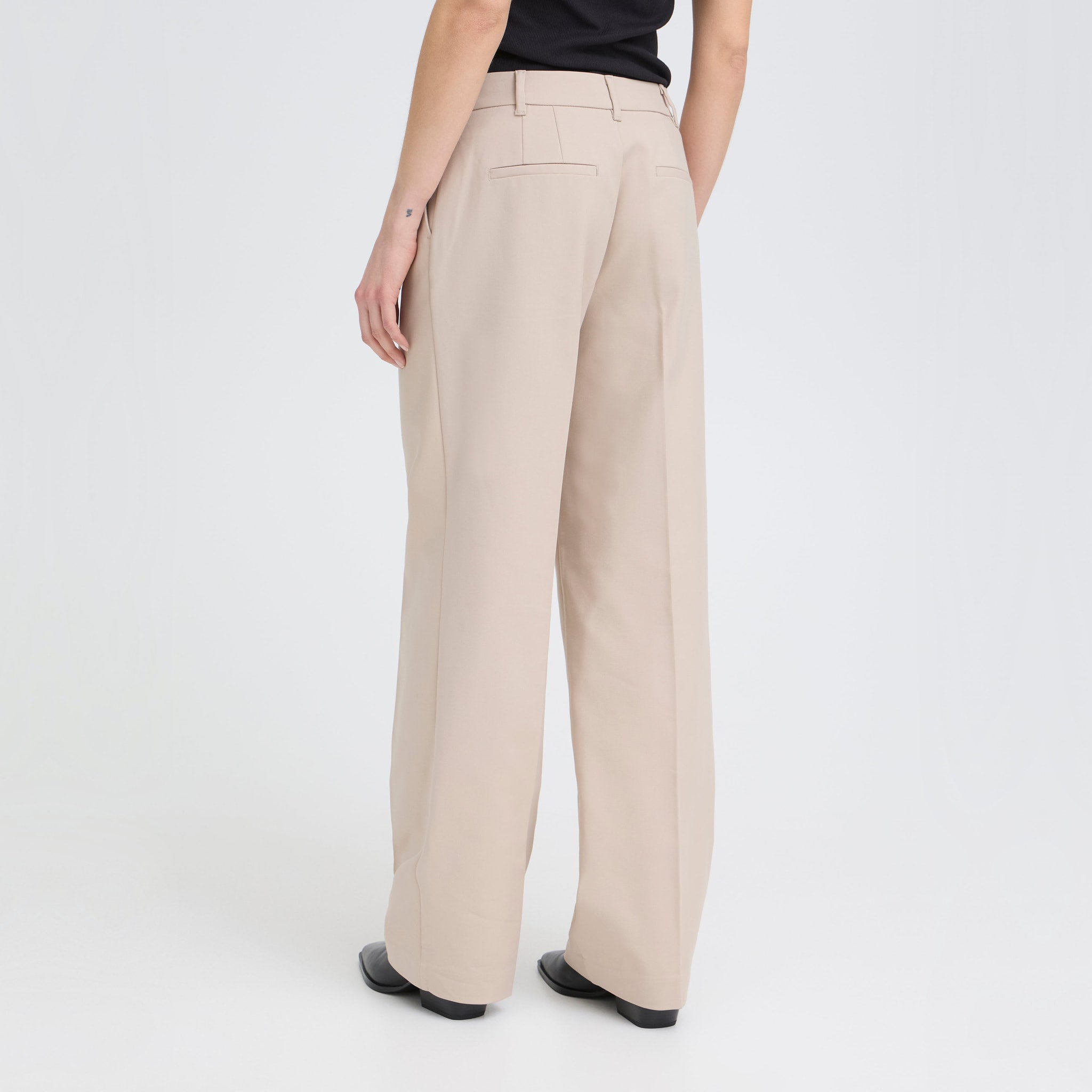 Model i beige wide leg bukser fra Pulz i fuld længde set bagfra
