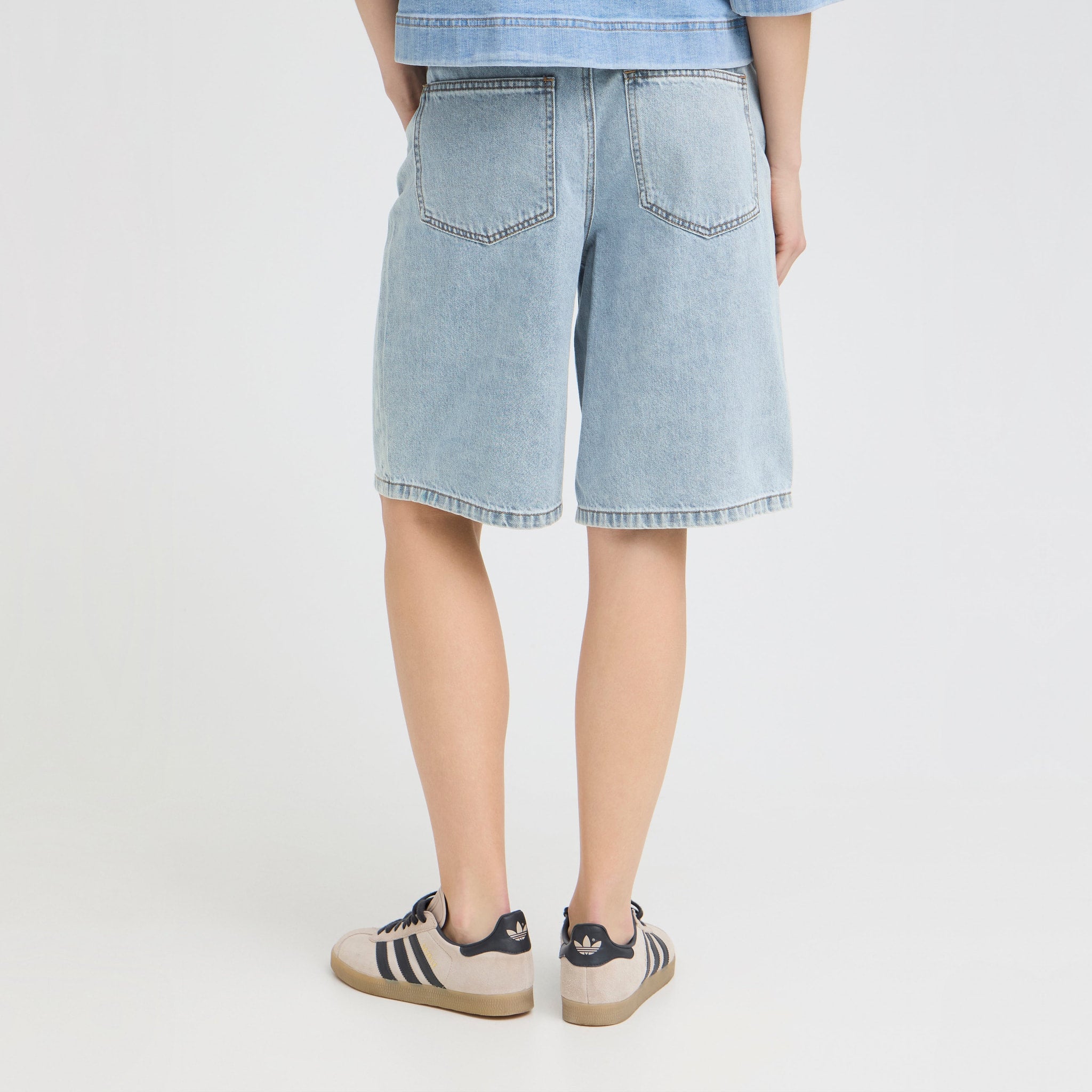 Model i lyseblå Bridget shorts set bagfra med to baglommer og længde til over knæet