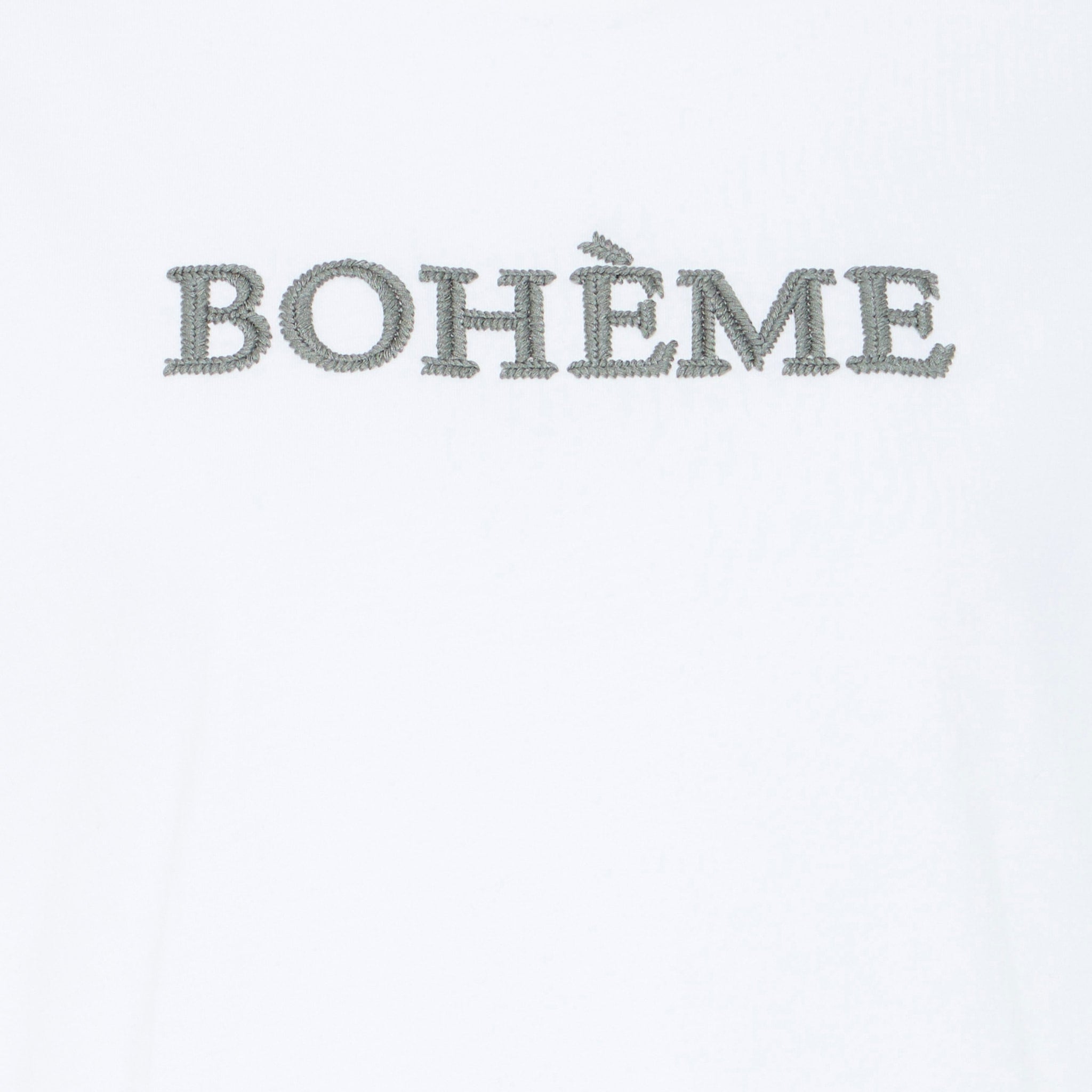 Nærbillede af den broderede grågrønne BOHÈME-skrift på hvid t-shirt