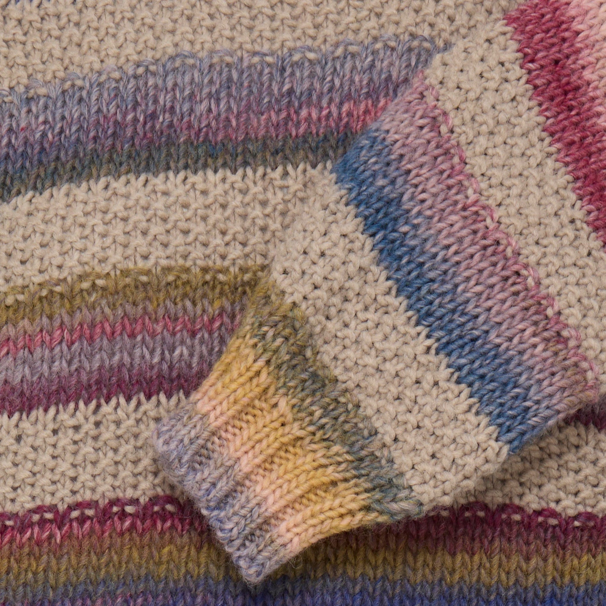 Nærbillede af strikken og ribkanten ved ærmet på den flerfarvede pullover