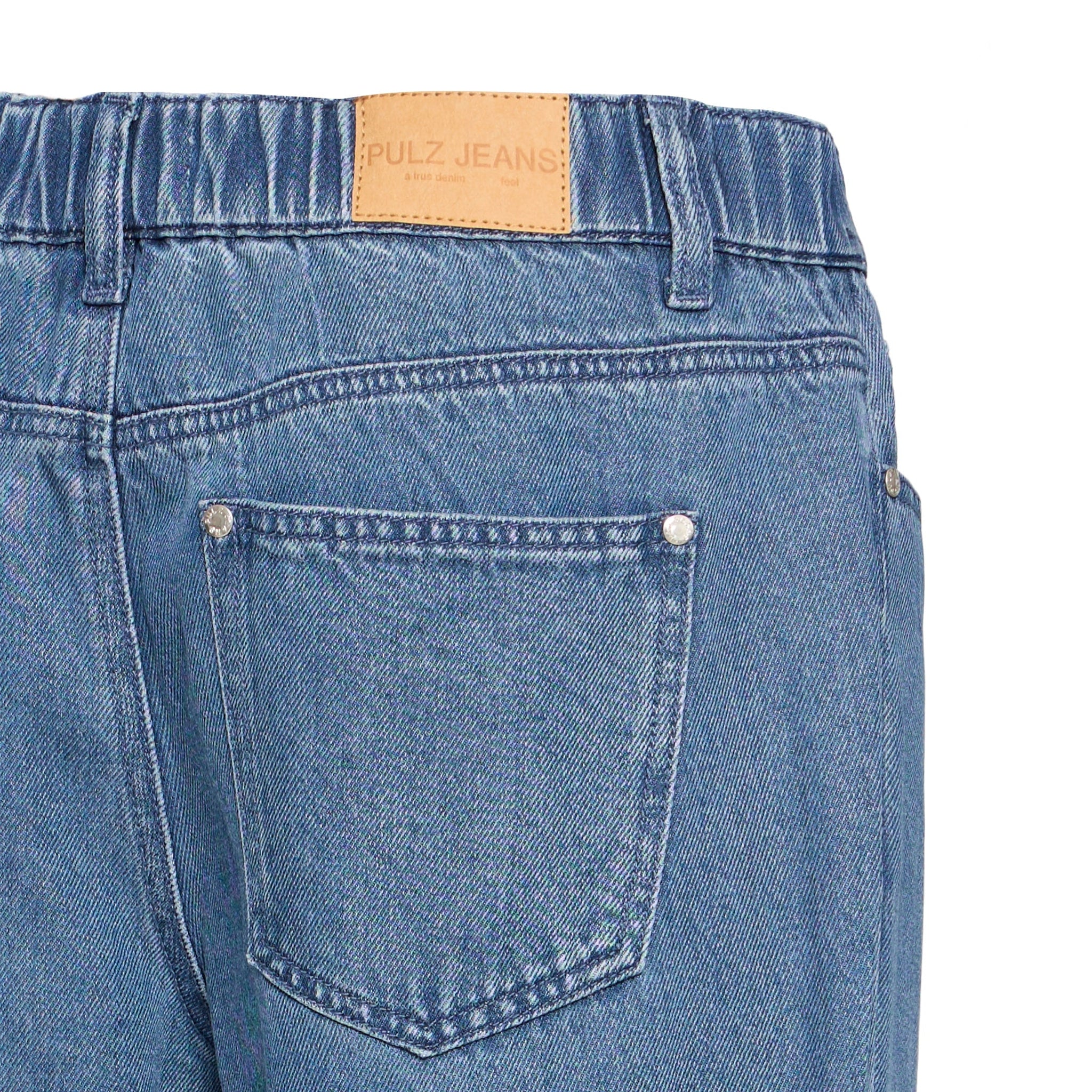 Nærbillede af baglomme, elastik i linningen og brunt PULZ JEANS-mærke på blå jeans