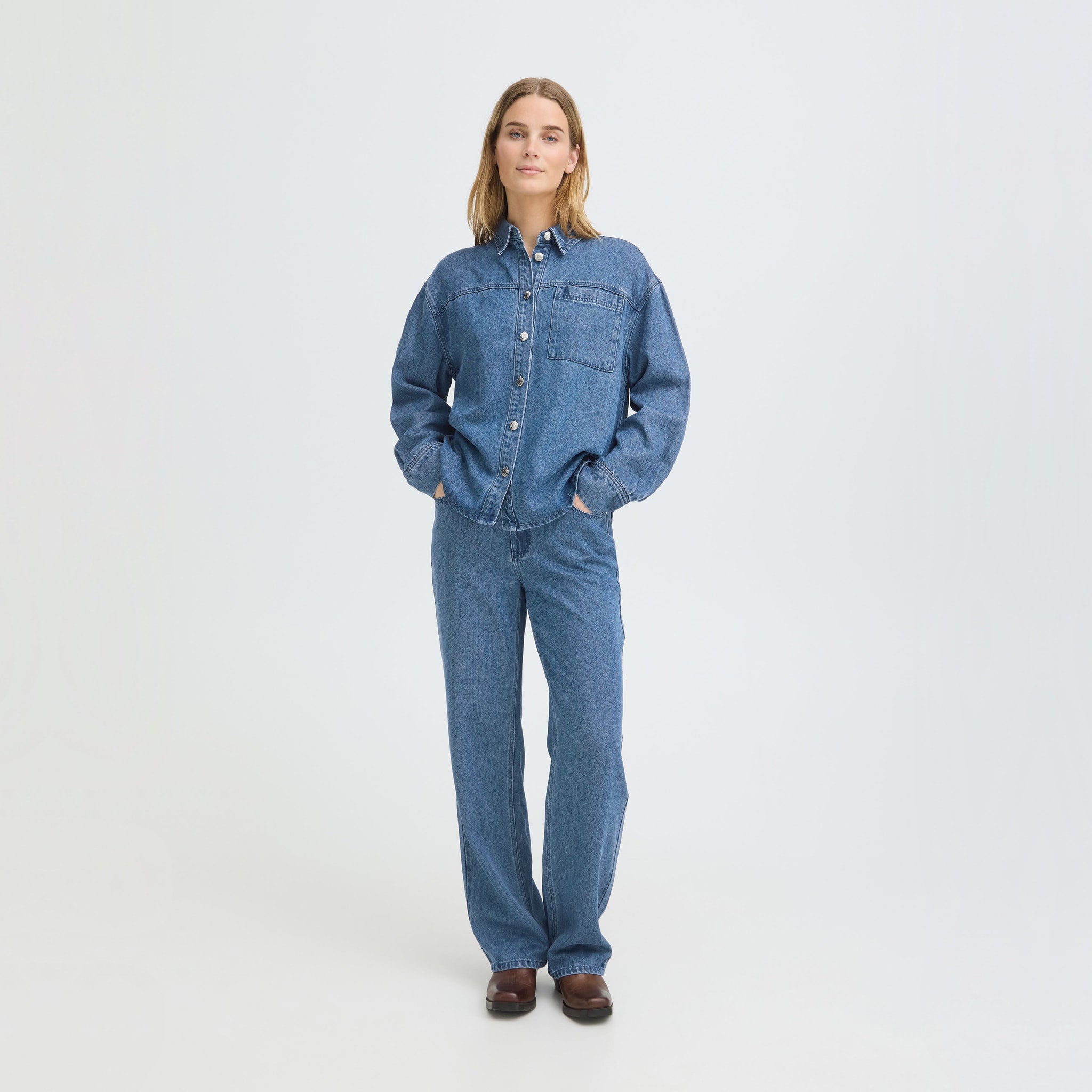 Model i blå wide leg jeans fra Pulz set forfra, stylet med denimskjorte og brune støvler