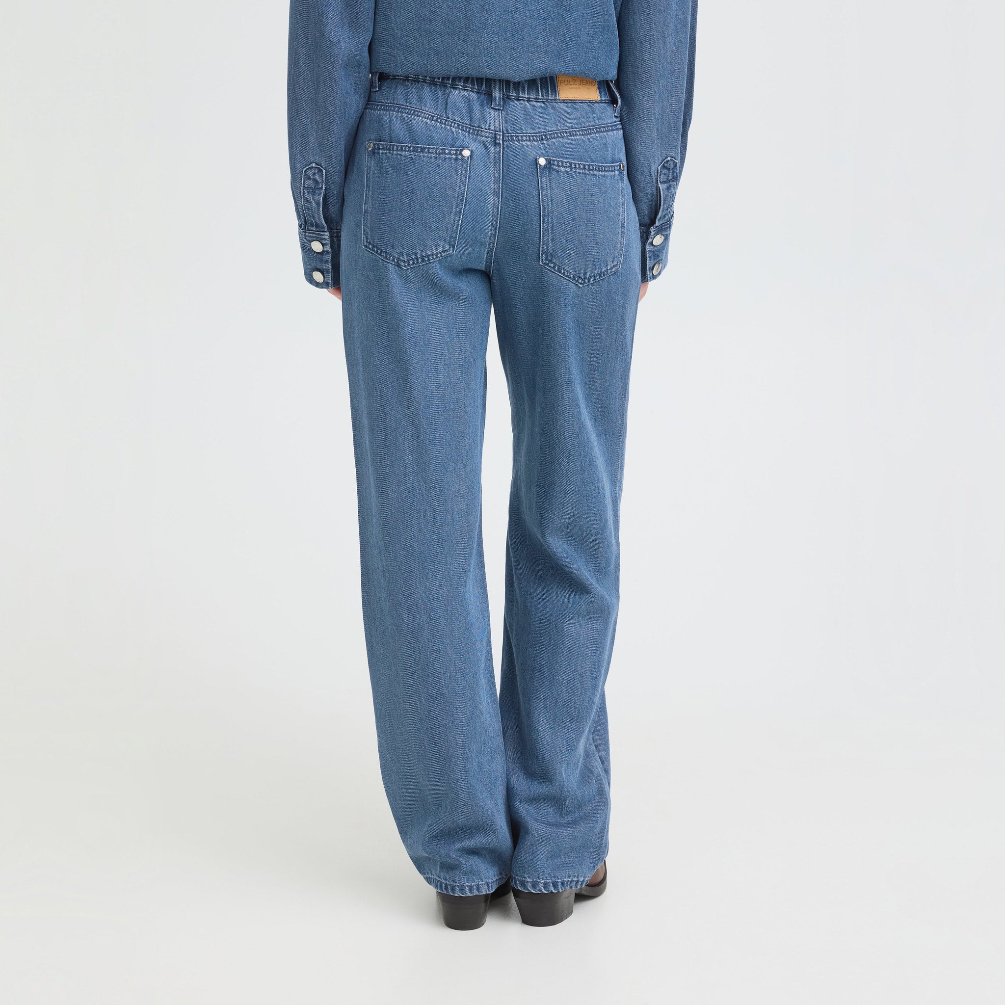 Model i blå jeans fra Pulz set bagfra med lige, vide ben og baglommer