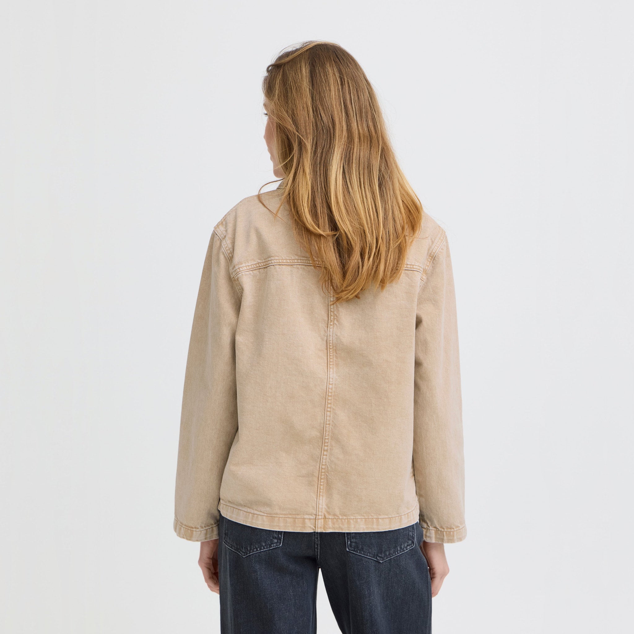Model i beige jakke fra Pulz med mørke jeans, set bagfra