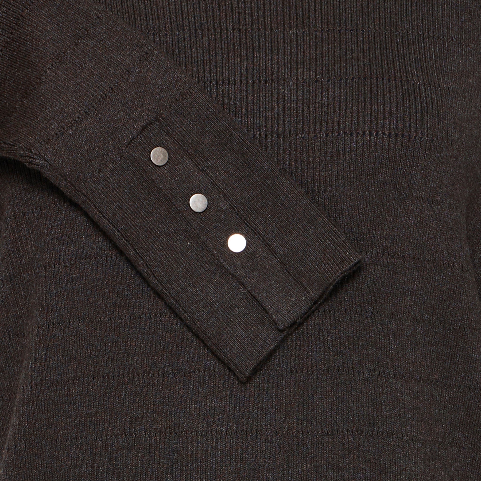 Nærbillede af ærmekant med tre sølvfarvede knapper og slids på brun pullover med hulstriber