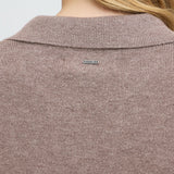 Detalje bagfra af brun pullover med ribbet krave og logoskilt i metal