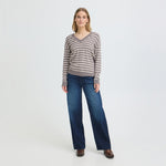 Model i brun stribet pullover med V-hals stylet med vide blå jeans og brune støvler