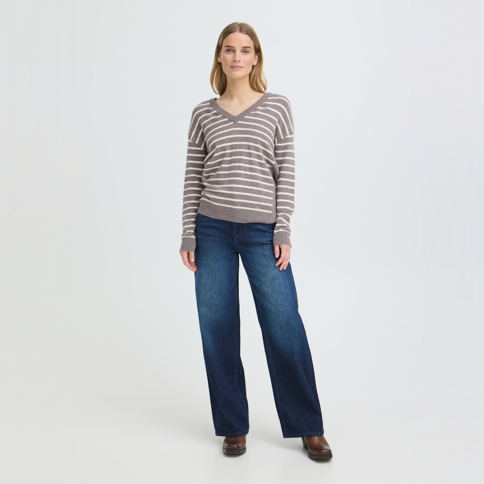 Model i brun stribet pullover med V-hals stylet med vide blå jeans og brune støvler