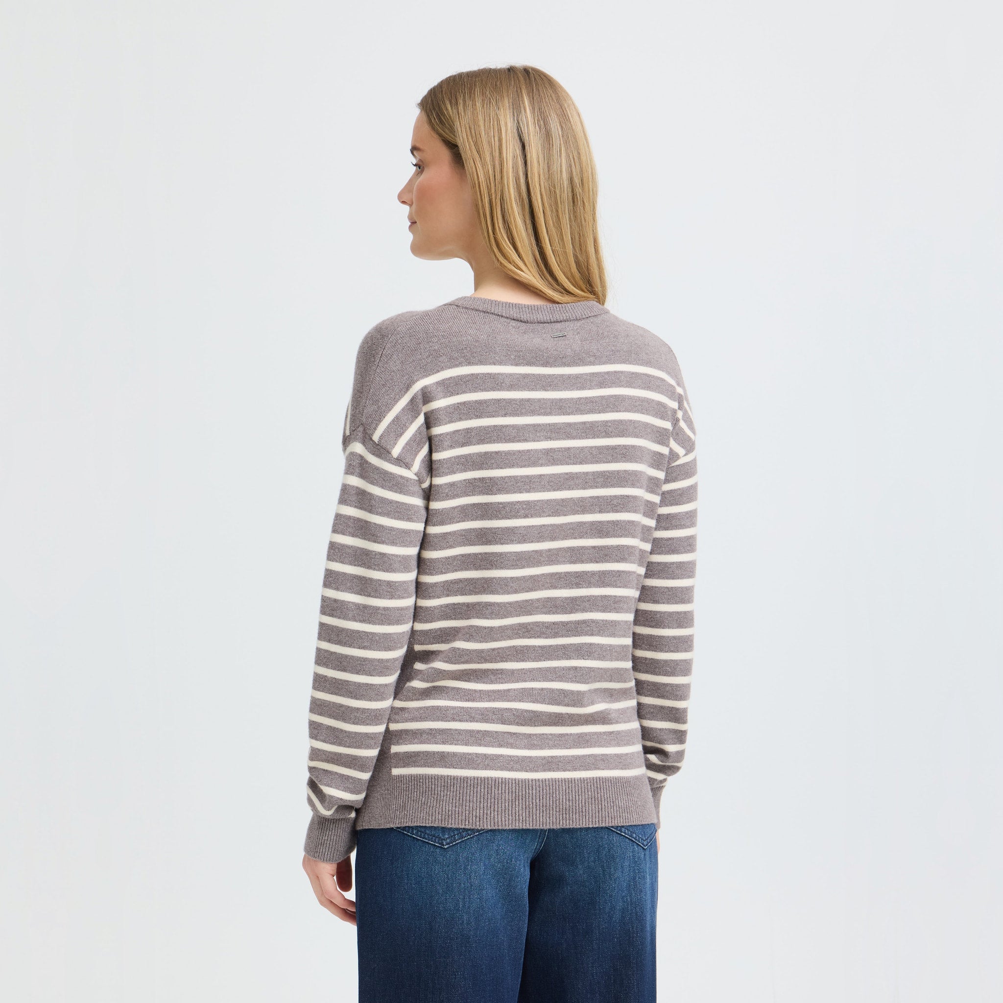 Model set bagfra i brun pullover med cremefarvede striber og lange ærmer