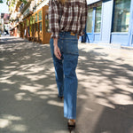 Model går på gaden i blå wide leg jeans set bagfra med ternet skjorte
