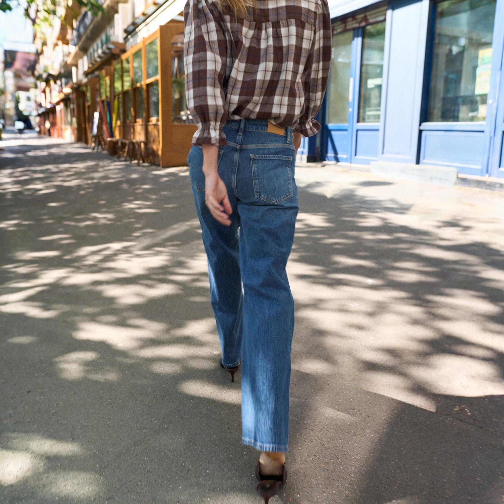 Model går på gaden i blå wide leg jeans set bagfra med ternet skjorte