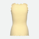 Gul ribstrikket top i silke og bomuld fra Rosemunde i farven Flan, set bagfra med blonde langs kanten og ærmegabene