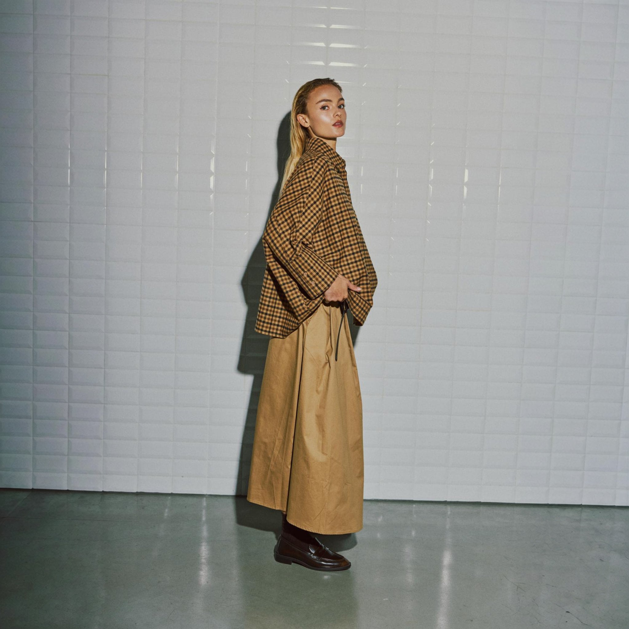 Brun midi nederdel i Dark Camel på model set fra siden med bæltet hængende ned