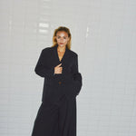 Model i stribet navy blazer med én knap, stylet med vide bukser i samme stribe, set forfra