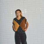 Model i beige harlekin vest med V-udskæring fra WithBlack, set forfra med vide mørke bukser